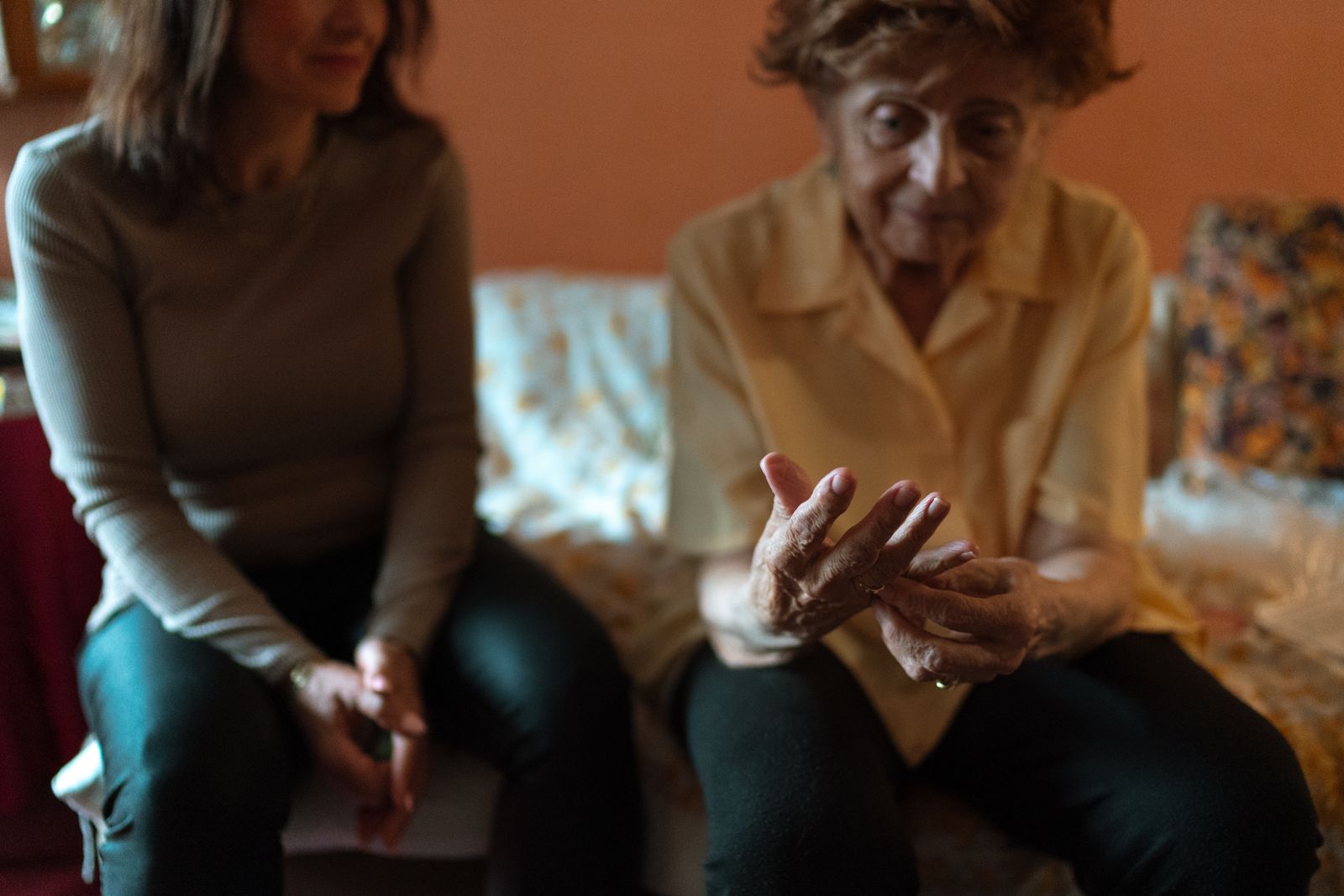 A caregiver sitting and talking with an older woman on her sofa at home